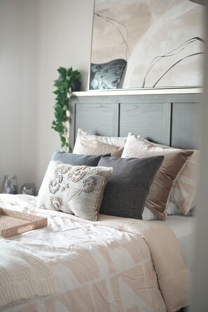 A bed with a patterned bedspread, multiple pillows, and a headboard. - Stylish 2BR/2BA OKC Apartment with Modern Decor, AC, Gym ,Pool & Plush Bedding (Oklahoma City)