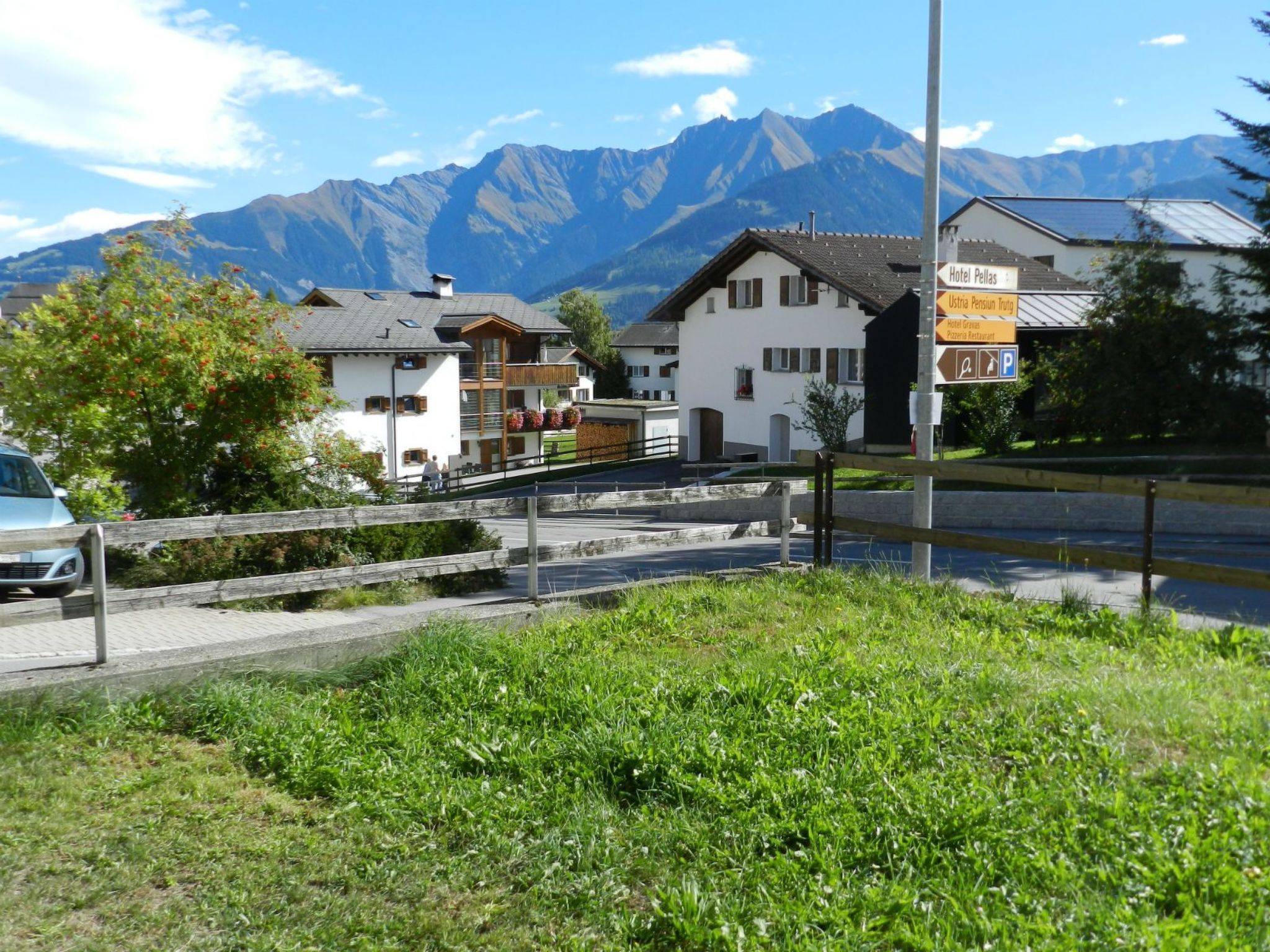 Un hôtel avec vue sur la montagne, un panneau indiquant les commodités à proximité et un pont piétonnier.
