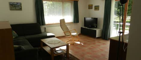 A living room with a sofa, a table, a TV, and a chair.