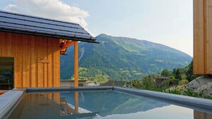 A modern wooden building with a glass-enclosed pool reflecting the surrounding landscape.