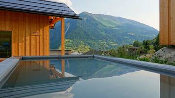 Ein Holzgebäude mit einem Glaspool, der die umliegende Landschaft spiegelt.