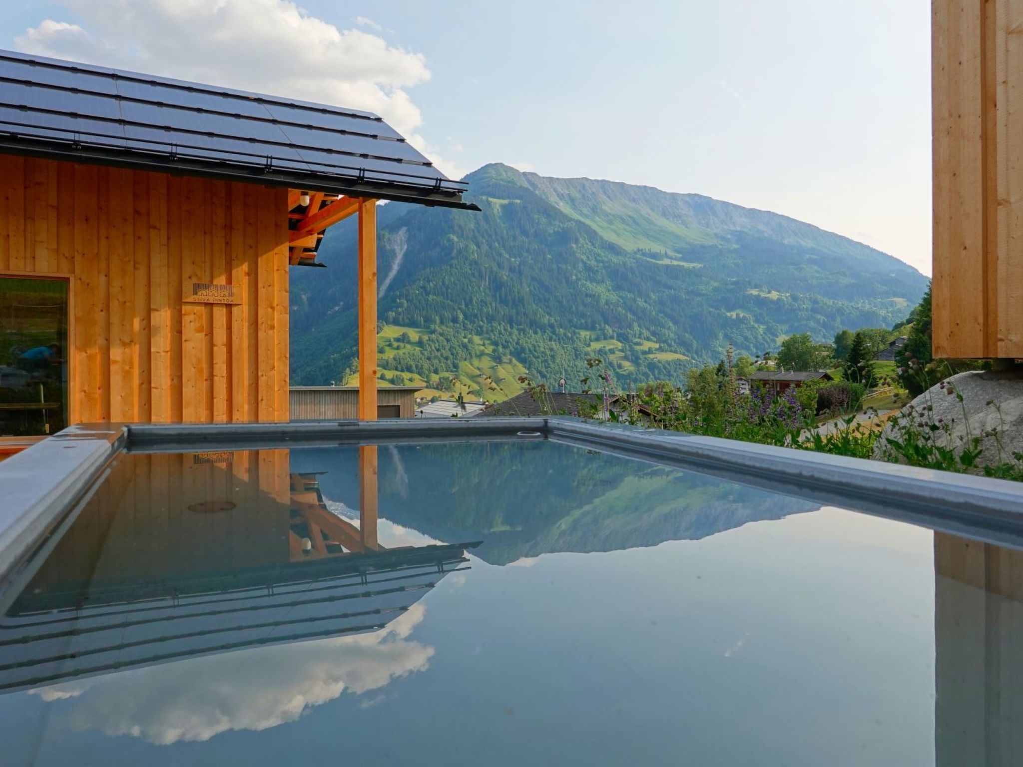 A wooden building with a glass pool reflecting the surrounding landscape.