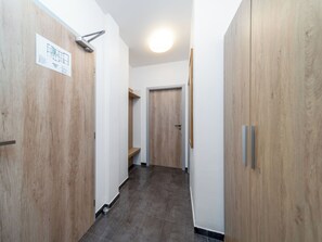 Ein Korridor mit Holztüren, gefliestem Boden und einer Deckenleuchte.