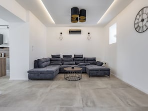 A modern living room with a sectional sofa, a coffee table, pendant lights, and a wall clock. - Vacation home Marko by Interhome (Pirovac)