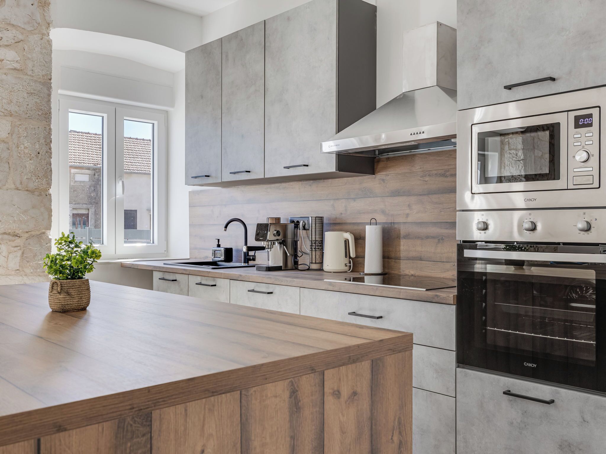 A modern kitchen with a large island, built-in appliances, and a view of the outside.