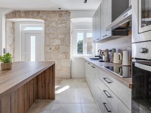 A modern kitchen with a stone accent wall, a wooden countertop, and built-in appliances. - Vacation home Marko by Interhome (Pirovac)