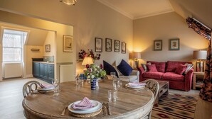 Un coin repas avec une table ronde, des chaises et un canapé rouge en arrière-plan.
