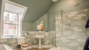 Une salle de bain moderne avec une douche à parois de verre, une baignoire sur pieds et une fenêtre laissant entrer la lumière naturelle.