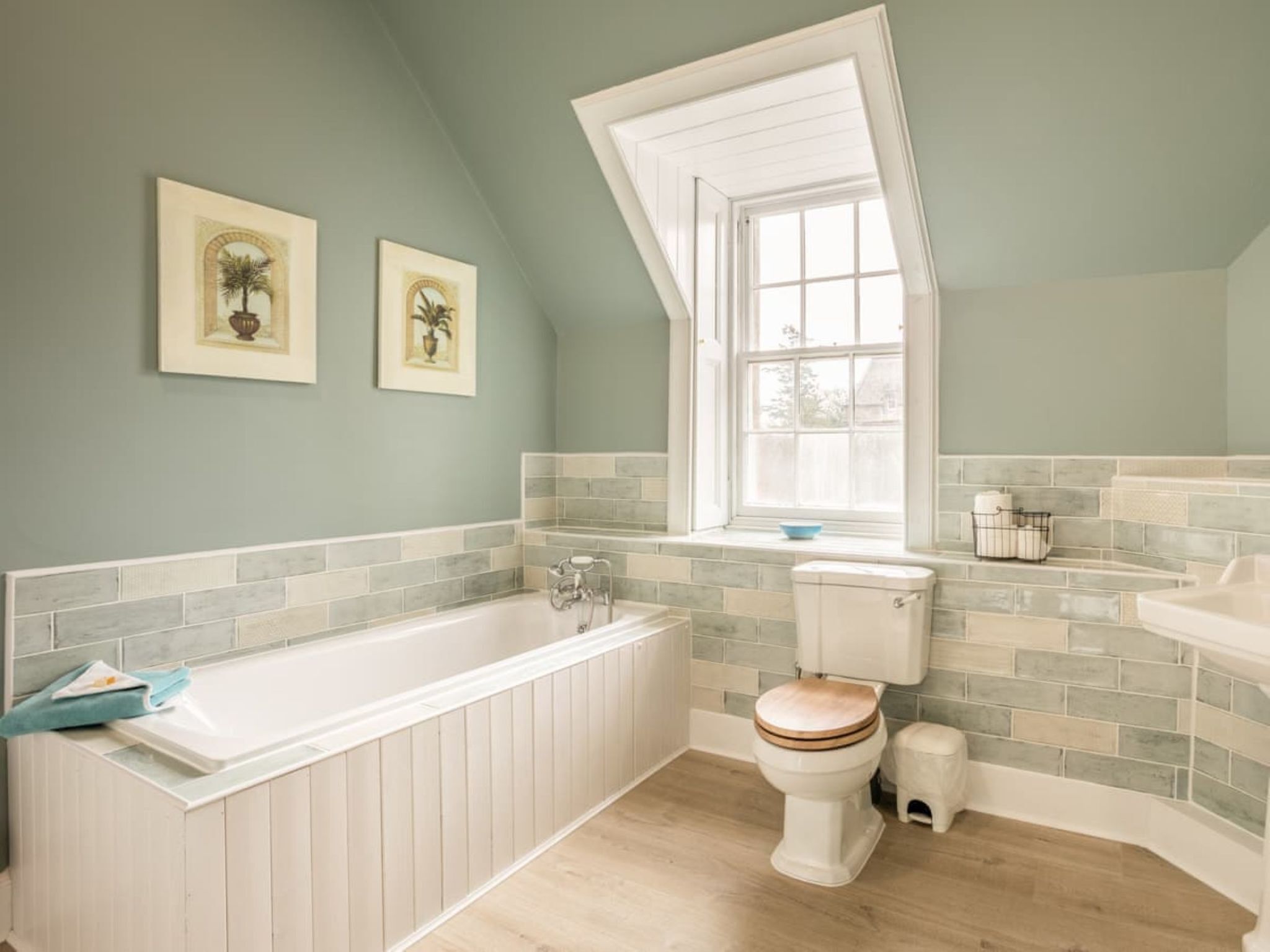 Een badkamer met een bad, toilet en een raam.