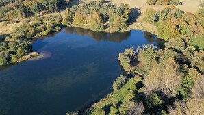 Une vue aérienne d’un lac entouré de forêts denses et d’un bâtiment situé au loin.
