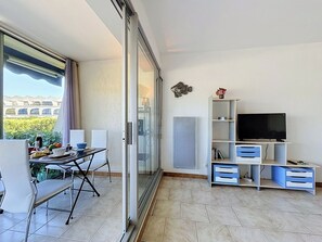 Uma sala de estar moderna com área de jantar, televisão e vista para o verde.