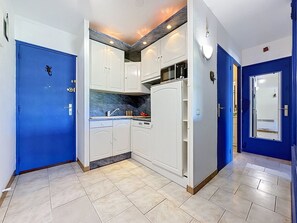 A kitchen with white cabinets, a blue door, and a tiled floor. - Les Jardins du Port by Interhome (Port Camargue)