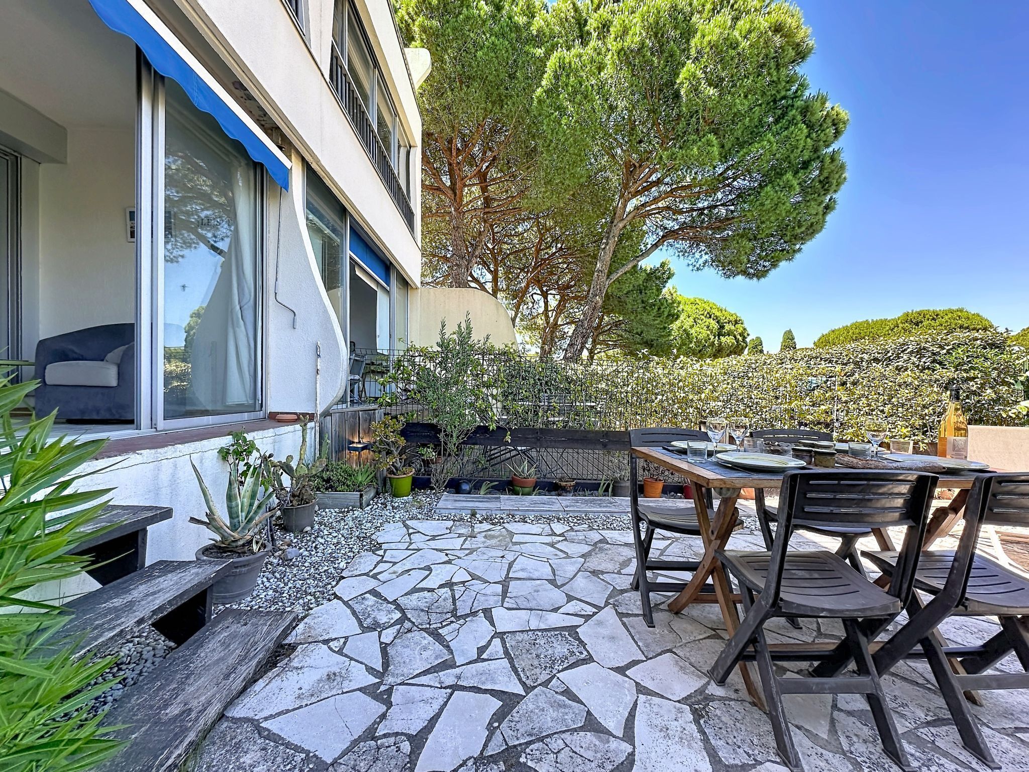 Uma área de pátio com piso de pedra, móveis de exterior e plantas em vasos.