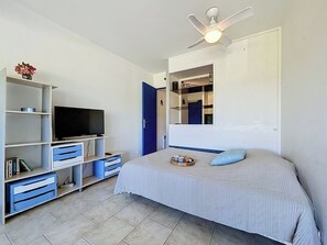 Ein Schlafzimmer mit Bett, Fernseher, Deckenventilator, Kleiderschrank und Spiegel.
