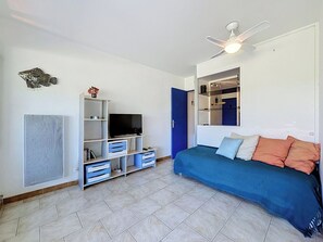 Um quarto com cama, televisão, ventilador de teto, guarda-roupa e porta.