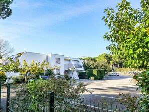 A modern building with a white facade, a gated parking area, and surrounding greenery. - Dixie Land by Interhome (La Grande Motte)