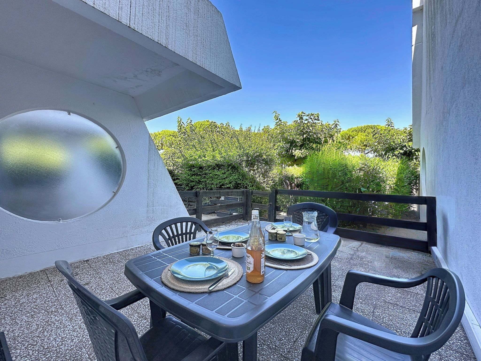 A table set outdoors with chairs, a glass bottle, and plates.