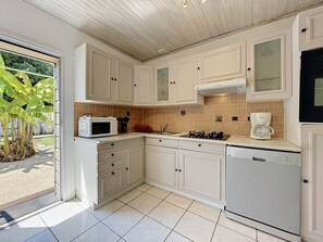 A kitchen with white cabinets, a microwave, a coffee maker, and a dishwasher. - L'Estuaire by Interhome (Saint Brevin les Pins)