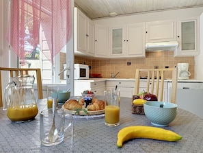 En morgenmadsopstilling med croissanter, en banan, en kande appelsinjuice og et glas appelsinjuice på et bord.