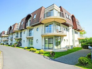 Ein modernes, mehrstöckiges Wohngebäude mit Balkonen, großen Fenstern und einem gepflegten Rasen.