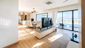 A modern living room with a TV, dining area, and large windows with a view.