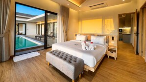 A modern bedroom with a large bed, a ceiling fan, a view of a swimming pool, and a separate bathroom area.
