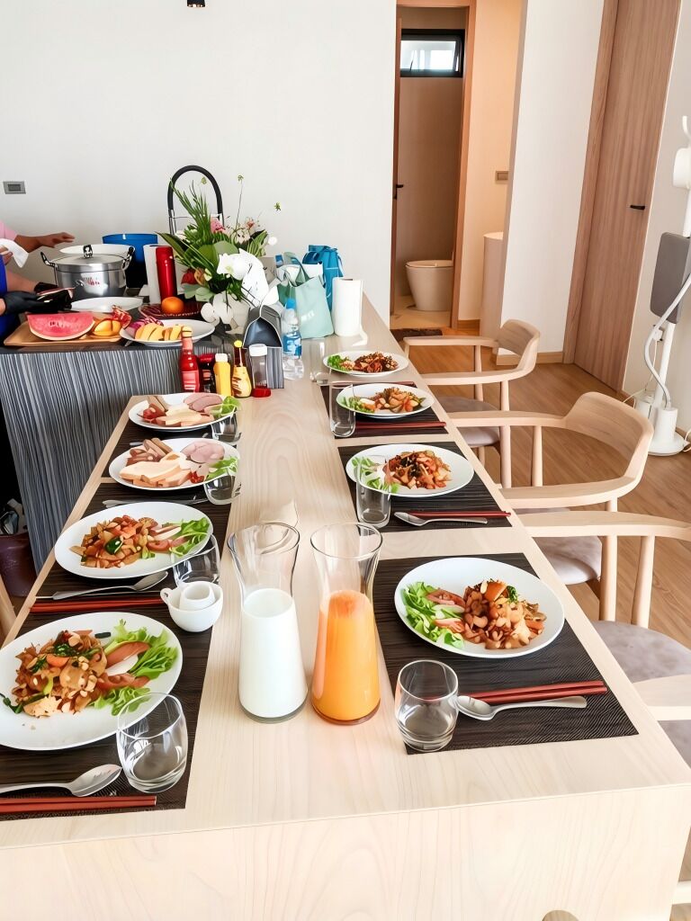 Una larga mesa de comedor con varios platos de comida, vasos y palillos.