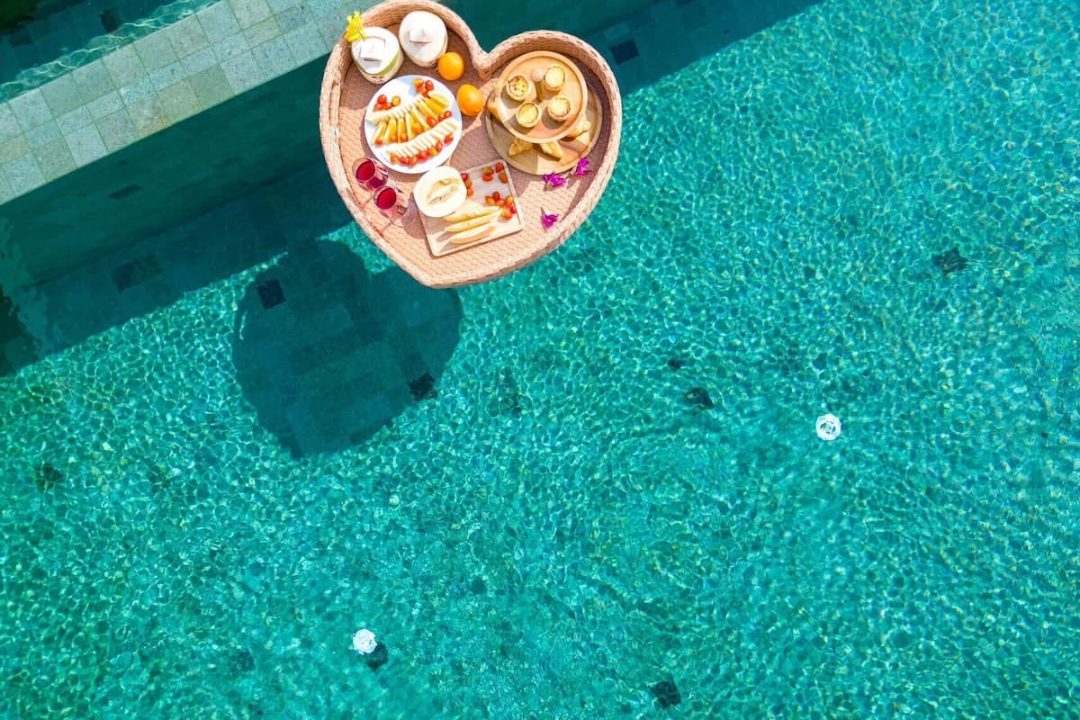 Eine herzförmige Platte mit Speisen und Getränken am Pool.