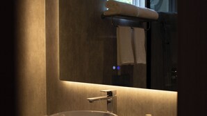 Un baño moderno con un lavamanos redondo, un espejo y una ventana.