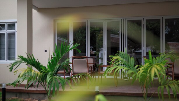 Un área de estar exterior moderna con terraza de madera, sillas y plantas en macetas.