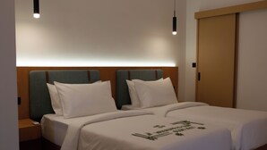 Una cama doble con cabecera de madera, mesitas de noche y un mueble auxiliar con control remoto.