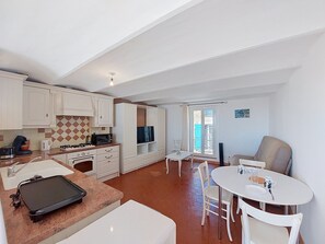 A compact living space with a kitchenette, dining area, and a sofa. - Bellevue by Interhome (Régusse)