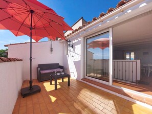 A patio with a red umbrella, a sofa, and a table. - Bellevue by Interhome (Régusse)