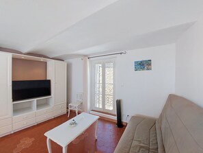 A living room with a TV, white furniture, a sofa, a table, a chair, and a window with a view. - Bellevue by Interhome (Régusse)