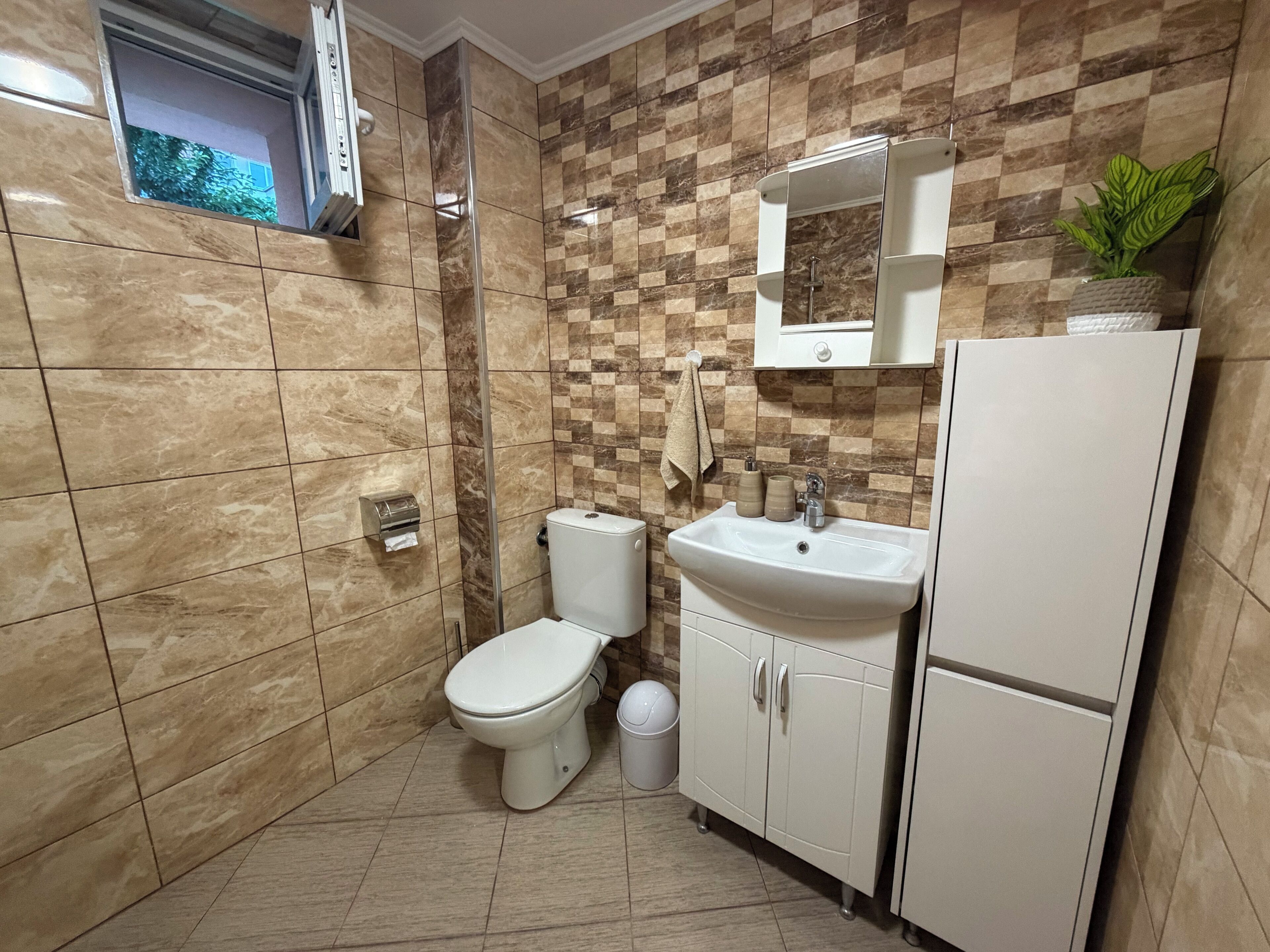 A bathroom with a toilet, sink, and cabinet.