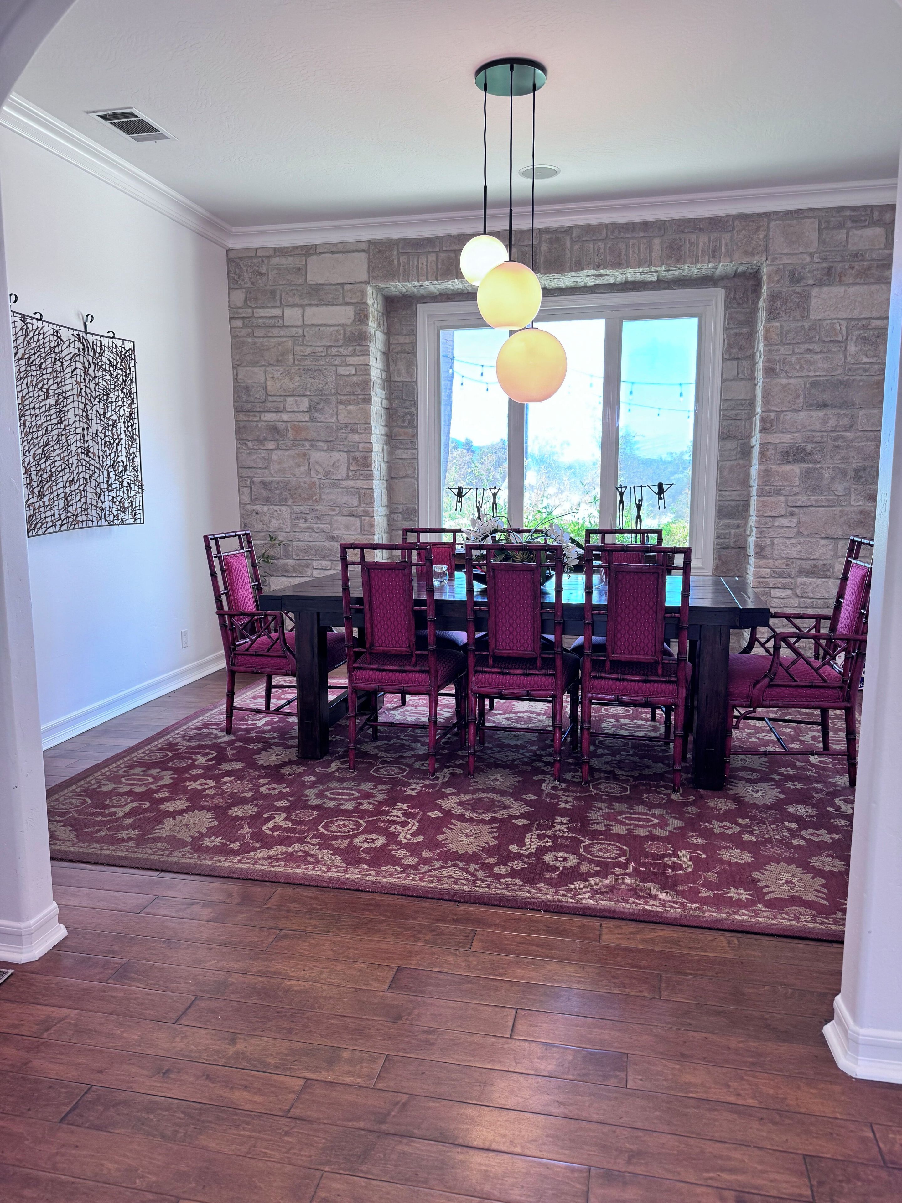 A dining area with a stone wall, a large window, and a table with chairs.