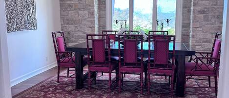 A dining area with a stone wall, a large window, and a table with chairs.