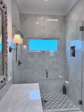 Ein modernes Badezimmer mit einer gläsernen Duschkabine, einem мраморной раковиной und einem gemusterten Boden.