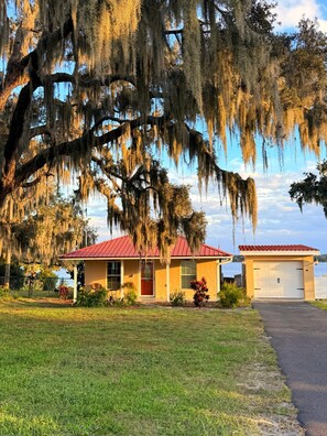 A house with a red roof, a garage, and a large tree with hanging moss. - Entire Lakefront House Getaway (Sebring)