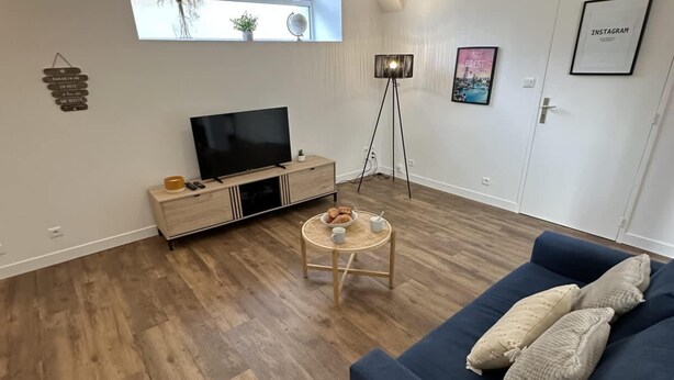 Un salon avec un téléviseur, un canapé, une table basse et un lampadaire.