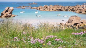 Un paysage côtier caractérisé par des formations rocheuses, une eau d’un bleu limpide et la présence de bateaux.