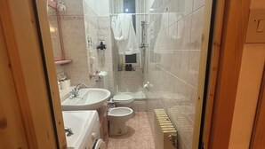 A bathroom with a sink, toilet, bidet, and a washing machine.