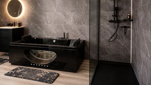 A modern bathroom with a freestanding bathtub, a glass-enclosed shower, and a round mirror with a light.
