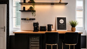 A modern kitchen with a built-in coffee station, black bar stools, and a framed photo on the counter.