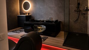 A modern bathroom with a vanity, a round mirror, a shower, and a heated floor.