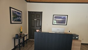 A reception desk with a Lenovo computer, a private door, a framed landscape picture, and a small table with a potted plant. - The Coolin Motel (Coolin)