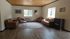 A spacious living room with a wooden ceiling, large windows, a fireplace, and leather sofas. - The Coolin Motel (Coolin)