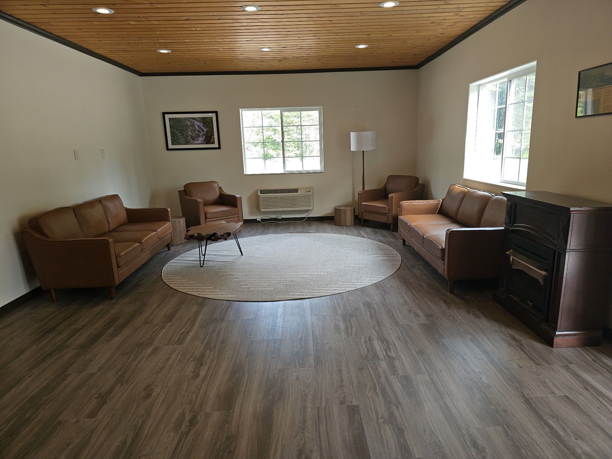 A spacious living room with a wooden ceiling, a large window, and a fireplace.