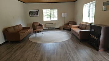 A spacious living room with a wooden ceiling, a large window, and a fireplace.