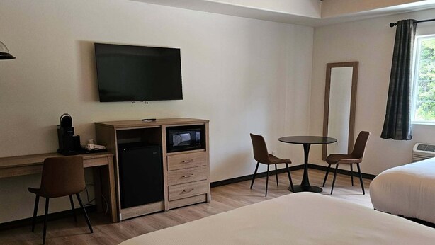 A hotel room with a bed, a desk with a TV, a microwave, and a chair. - The Coolin Motel (Coolin)